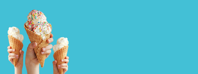 Hands holding a vanilla ice cream cone on blue background.
