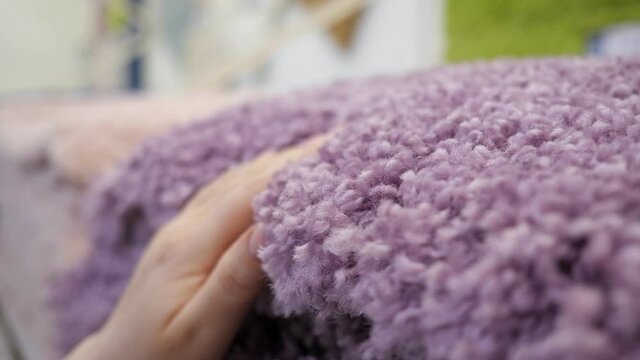 close-up of female hand stroking purple shaggy carpet.