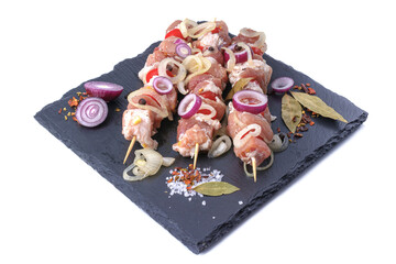 Raw pieces of pork shish kebab in marinade with pepper, onion,bay leaf.Pork kebab, ready to cook, barbecue, isolated on a white background.Selective focus.