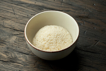 Appetizing Asian side dish - boiled white Thai rice in a white bowl on a wooden background. Vegetarian food