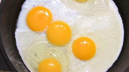 The process of frying chicken eggs in a frying pan.