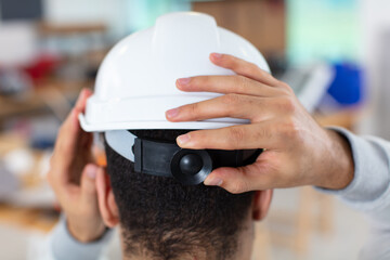 workman adjusting his hard hat to fit correctly