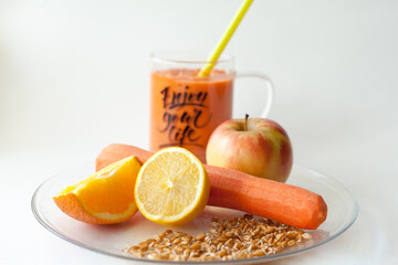 Orange smoothie made from healthy vegetables and fruits in a beautiful transparent mug on a white background. Healthy lifestyle. Contains carrot, orange, lemon, apple, wheat germ. Enjoy your life