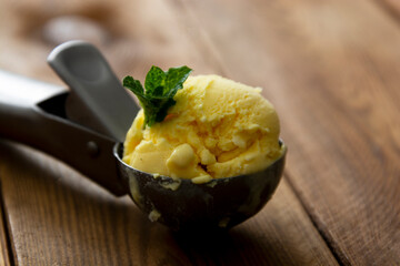Ice cream closeup scoop, round icecream ball in scoop spoon on rustic wooden background