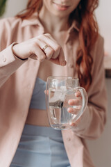 girl brews tea in a bag in a transparent cup