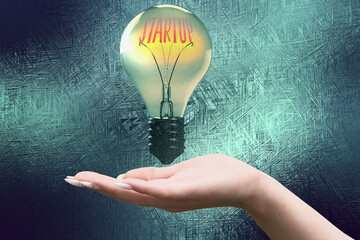 Eine Hand, Glühbirne und Startup Unternehmen