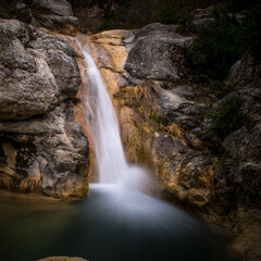 Fototapeta na wymiar une cascade en corse en vitesse lente avec la vitesse de l'eau traduite par un flou le long des rochers luisants