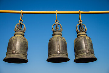 Fototapeta premium Steel bells hang on bar in buddhist temple with blue sky