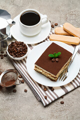 Portion of Traditional Italian Tiramisu dessert and savoiardi cookies on grey concrete background