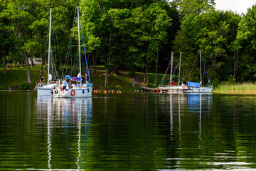 Fototapeta na wymiar Yachts moored in a beautiful lake bay. Sailboats in the dock. Summer vacations