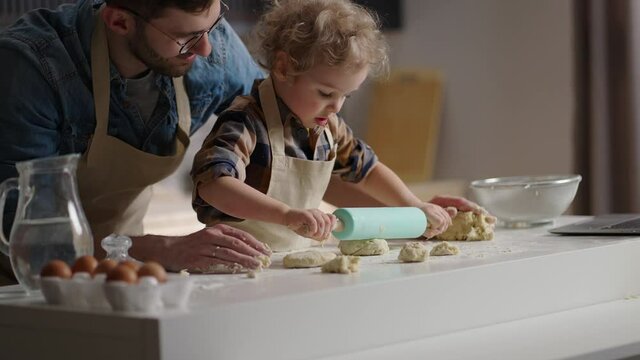father is playing with his little son at kitchen, teaching to cook and to do household chores, happy family