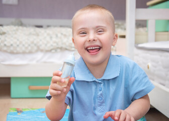 Portrait of a cute boy with Down syndrome, a child laughing, children andwalids.
