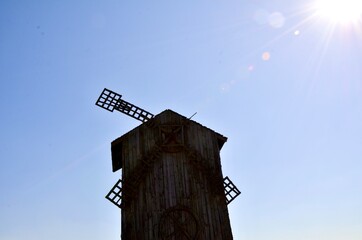 Wooden old mill in the sun. The bright summer sun shines on a beautiful mill. An old mill.