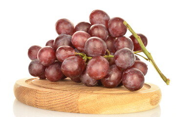 A bunch of fresh organic, juicy, ripe, sweet grapes on a round bamboo tray, close-up, on a white background.