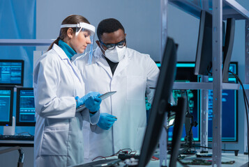 Diverse team of microelectronic engineers discuss current developments in a science lab. Workplace...