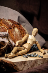 The mannequin for drawing lies on a wooden board next to bread and a jar of biscuits on a brown background. 