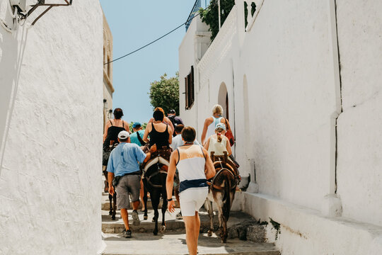 Group Of People Walking Through A Town In Greece