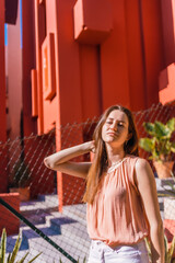 Young caucasian woman enjoying the summer on a background orange house