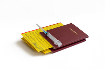 A tourist's passport with a yellow vaccination certificate. On top of the passport is a syringe. The concept of travel restrictions for people without vaccination against the COVIND-19 coronavirus.