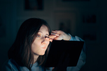 Fototapeta na wymiar Tired Woman Rubbing Her Eyes Holding Tablet Sitting in Bed