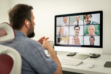 Mid adult man having online conference working at home