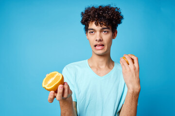 joyful man in blue t-shirt with oranges in hands studio isolated background