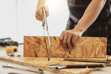 Male carpenter builder working with wooden board in the workshop to decorate the woodwork.
