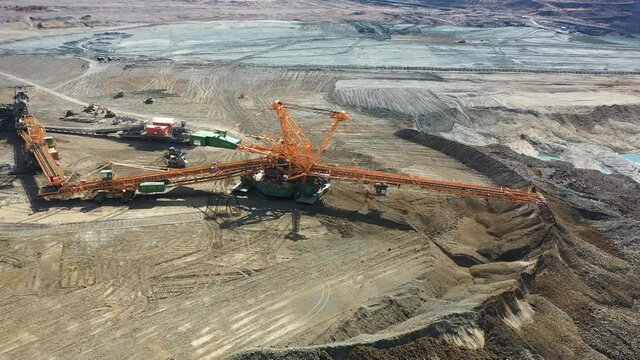 Aerial view of heavy machinery on lignite open pit coal mine dragline excavators and trucks, orbit drone shot