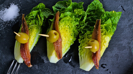 Aperitivo típico español de cogollos de lechuga con anchoas y aceitunas llamado perdices,...