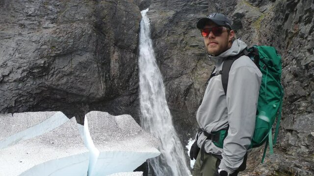 Male hiker with sunglasses looking at the famous waterfall, Silverfallet, Northern Sweden.