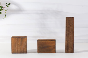 Natural wooden podiums for organic eco frinedly cosmetic products with green leaves against light background. Copy space