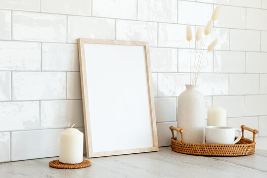 Wooden frame mockup and home decor on table in living room. Tiles bricks on background. Nordic, Scandinavian style.