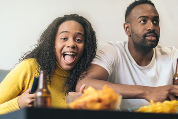 afro-american couple smiling and drinking beer at home