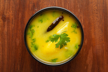 close-up of healthy curry of yogurt and potato (Dahi Aloo or Aaloo ) an Indian Classical dish. Served in Black bowl. Over Wooden Background and jute mat. Top view