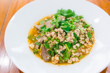 Spicy minced pork salad is traditional food of Northeast of Thailand. It contains minced pork, roasted rice, roasted chili and Thai herbs mixed together. It was put on white plate.