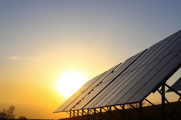 Photovoltaic batteries at orange sunset. Solar panels. Alternative energy concept