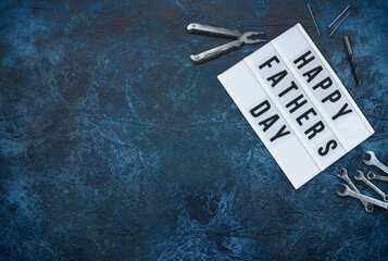 Happy Father's Day, a dark blue background with tools to the right  and left side of the writing. Top view. 