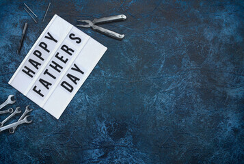 Happy Father's Day, a dark blue background with tools to the left and right side of the writing. Top view.