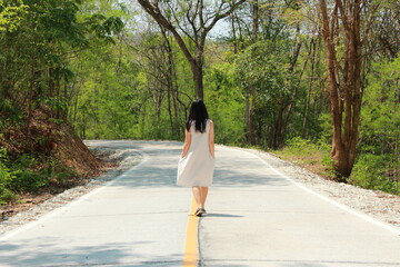 woman walking in the road which is way into the wood