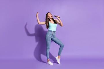 Full body photo of cute happy positive young lady hold mic sing karaoke song isolated on violet color background