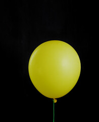 Beautiful yellow balloon on black isolated background. Layout