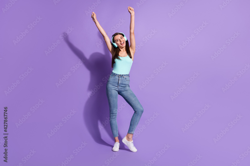 Poster Full body photo of happy brunette woman raise hands dance listen headphones song isolated on violet color background