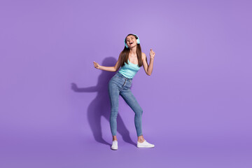 Full size photo of young attractive charming positive smiling girl in headphones dancing isolated on violet color background