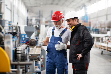 Portrait of workers in factory. Colleagues with helmet working in factory