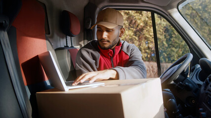 Courier using laptop in the van to confirm delivery address. High quality photo