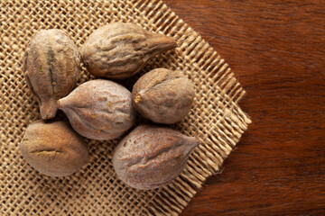 Macro close-up of Organic baheda (Terminalia bellirica) on wooden top background and jute mat. Pile of Indian Aromatic Spice. Top view