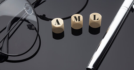 Anti Money laundering concept, words on wooden blocks on the black background with pen and glasses.