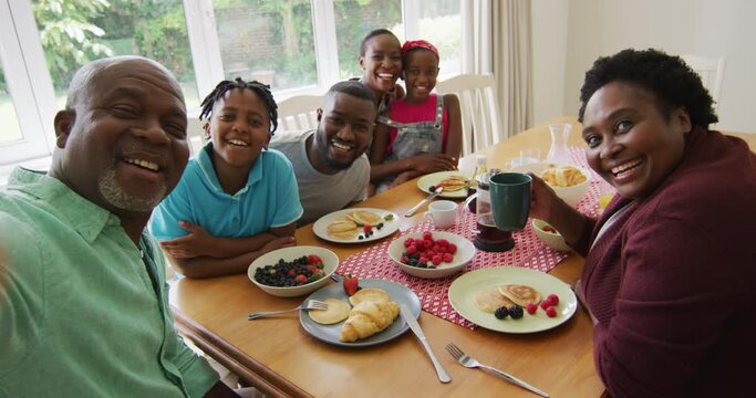 Three generation african american family taking a selfie while having breakfast together at home - Powered by Adobe