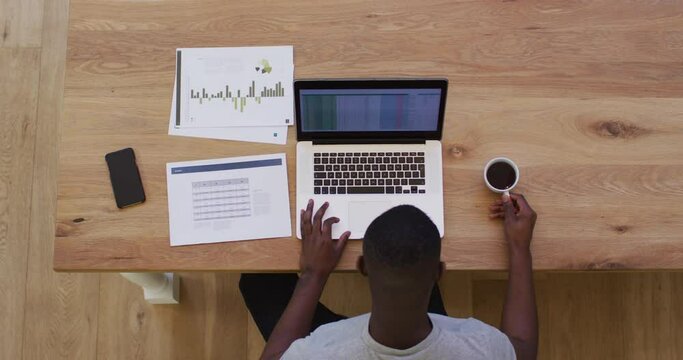 Overhead View Of African American Drinking Coffee And Using Laptop While Working From Home