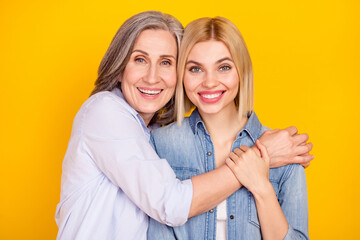 Photo portrait of mother and daughter spending family time embracing each other smiling isolated vivid yellow color background